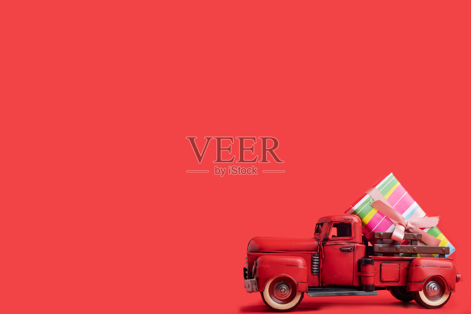 红色拖拉机在红色背景上运送装有礼物的箱子。横幅,留有文字空间。照片摄影图片