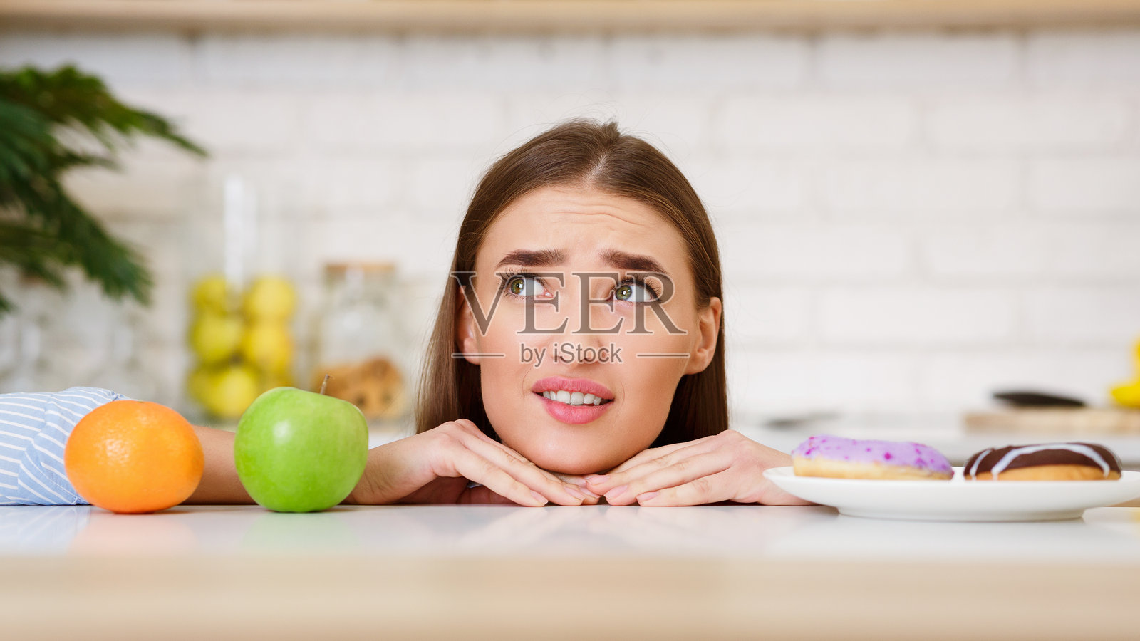 年轻女性在水果和甜点之间做选择照片摄影图片