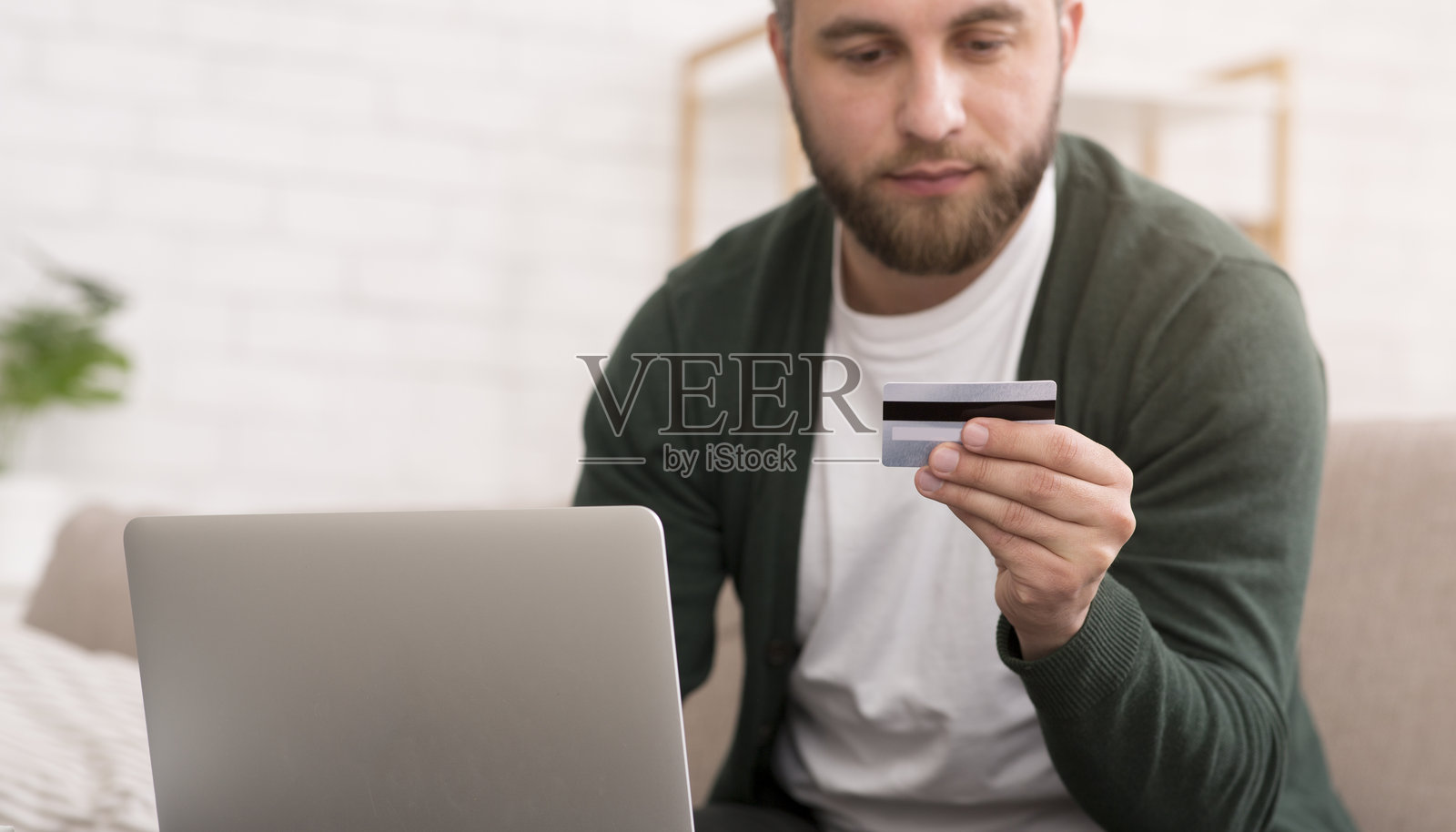 男人在家中晚上使用笔记本电脑检查信用卡信息照片摄影图片