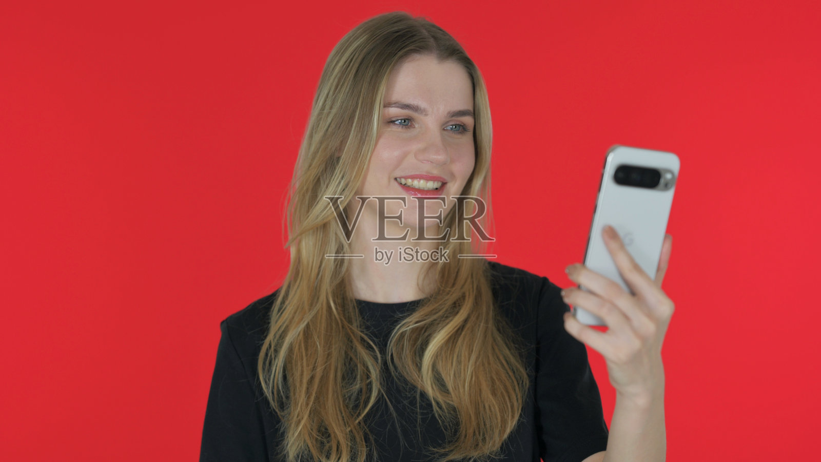 年轻女性在红色背景下用平板电脑进行视频聊天照片摄影图片