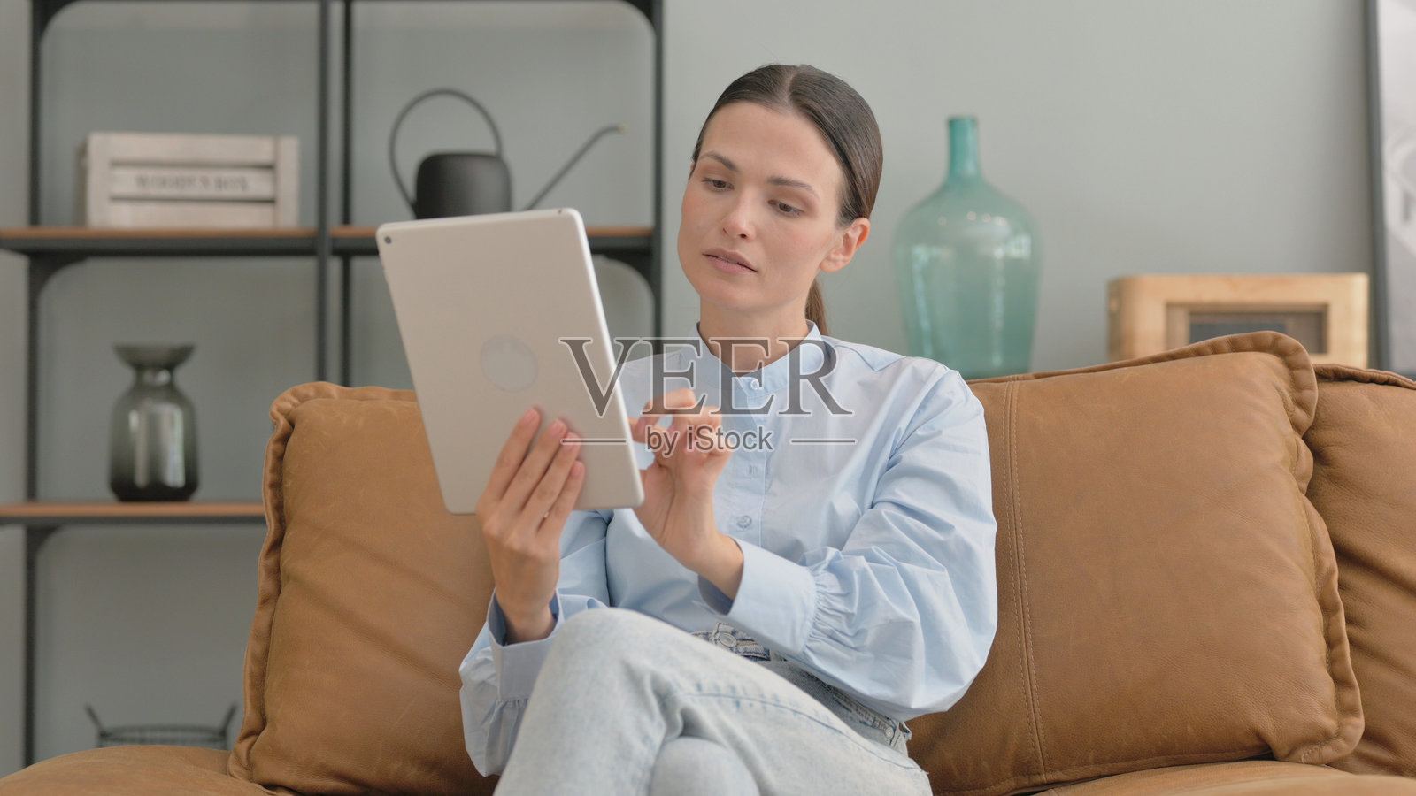 女人坐在家里的沙发上使用平板电脑照片摄影图片