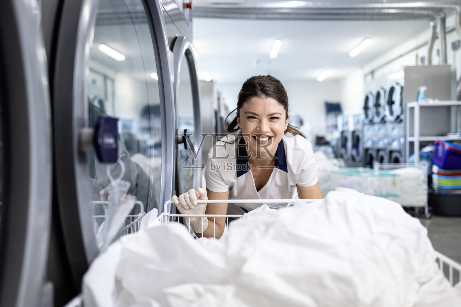 快乐的干洗工人与洗衣服。照片摄影图片