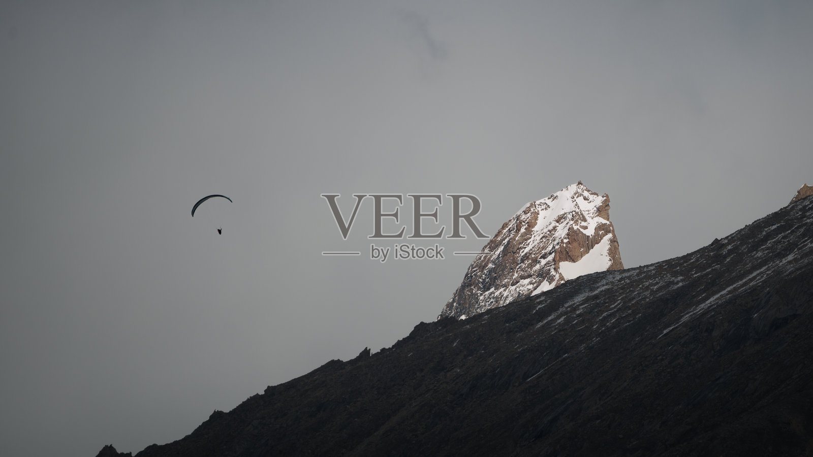 滑翔伞飞越巴尔托罗冰川和喀喇昆仑山脉的雪山顶峰,巴基斯坦照片摄影图片