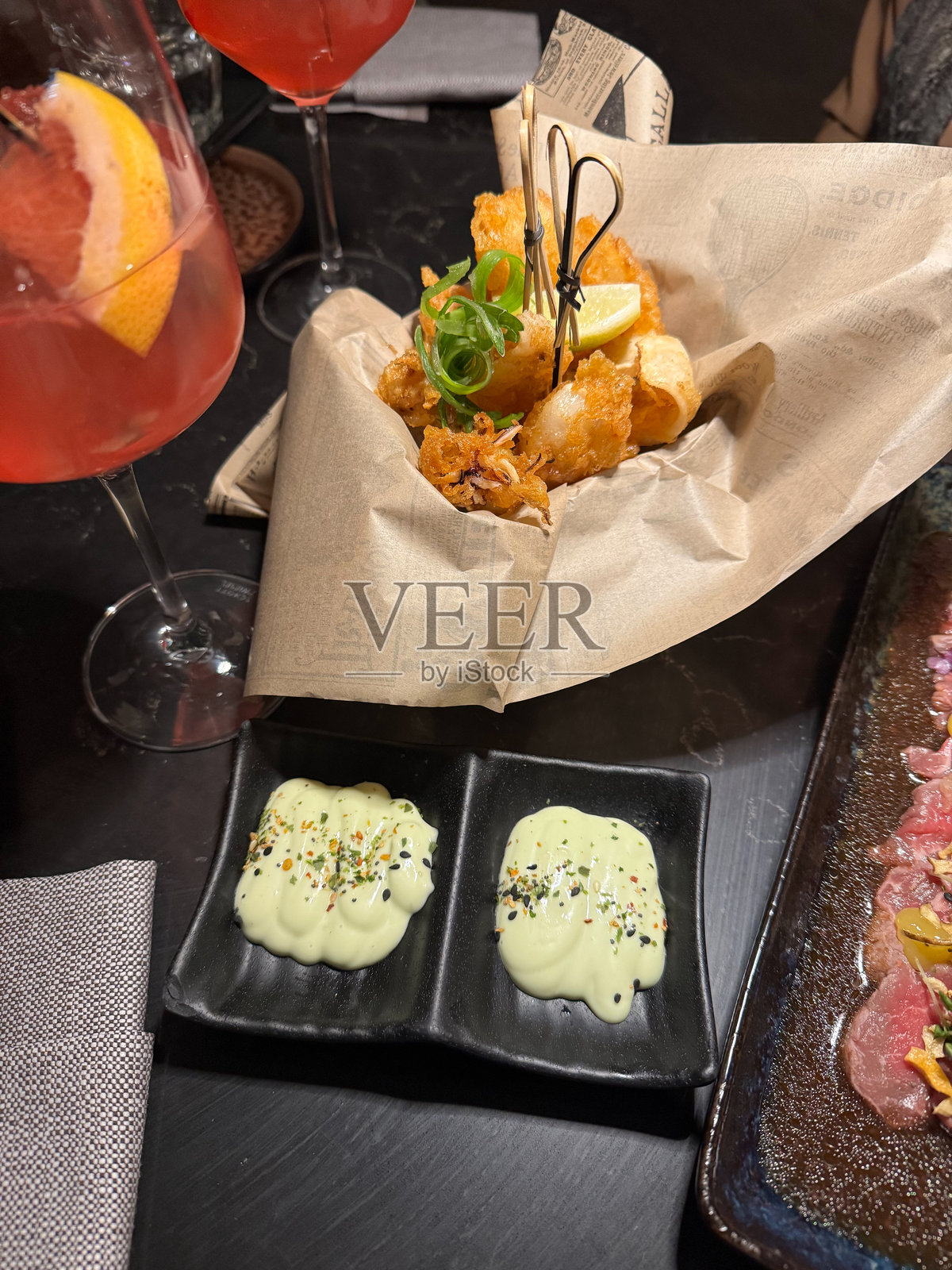 脆炸鱿鱼开胃菜盘,配有芥末美乃滋和蒜味艾奥利,供应于提供泛亚美食的高档餐厅晚餐。照片摄影图片