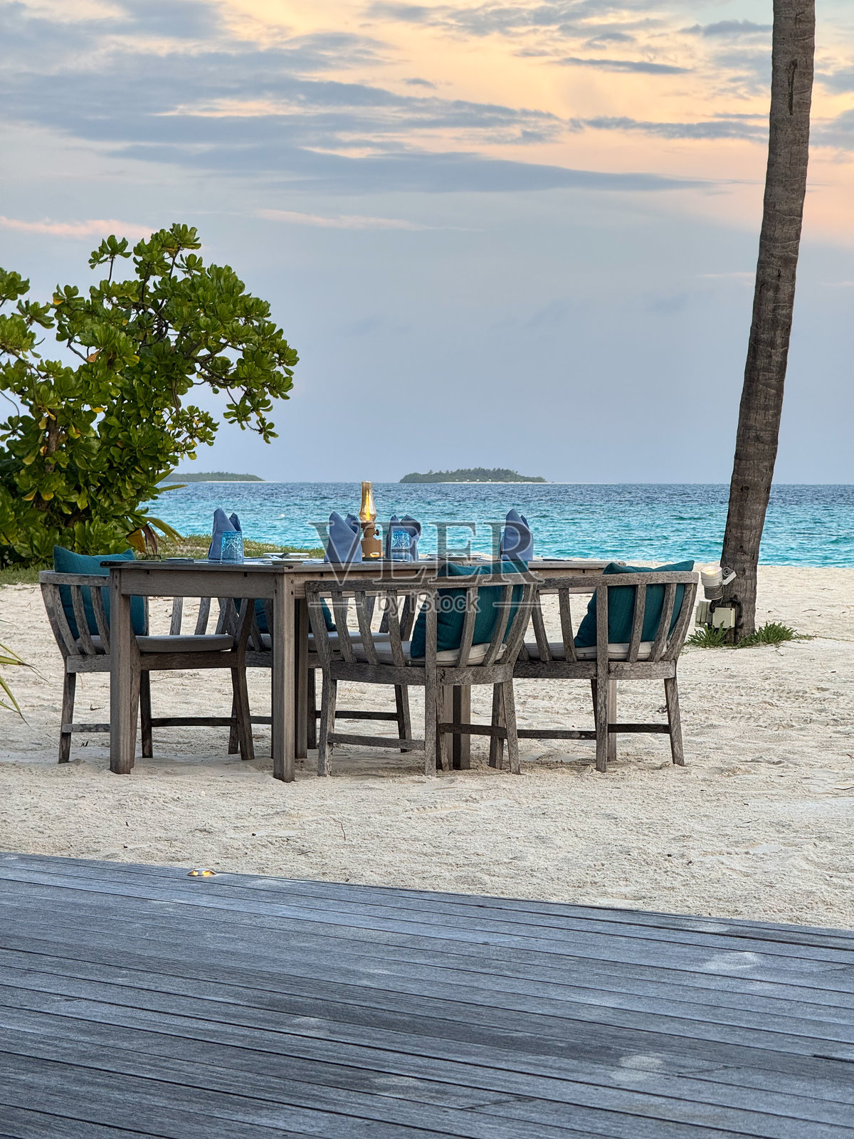 马尔代夫户外餐厅,海滩上的木桌餐饮布置,棕榈树下,享有豪华酒店度假村的海景照片摄影图片