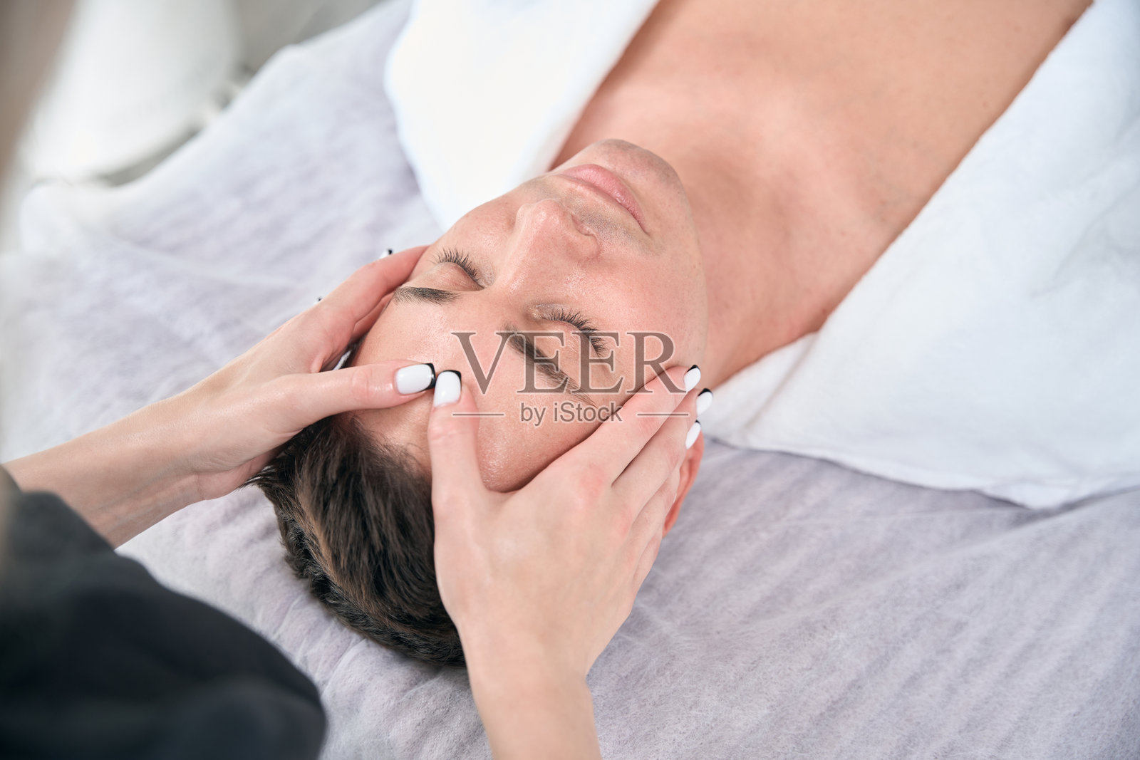 物理治疗师在医疗办公室为男性进行面部按摩的特写镜头照片摄影图片
