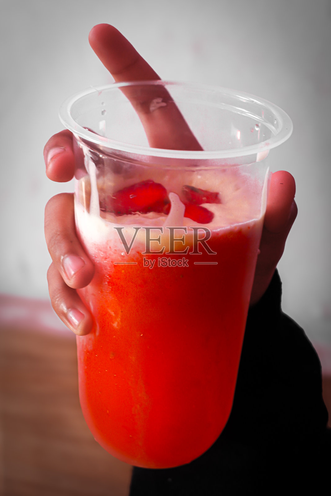 手握一杯冰冷的草莓奶昔饮料照片摄影图片