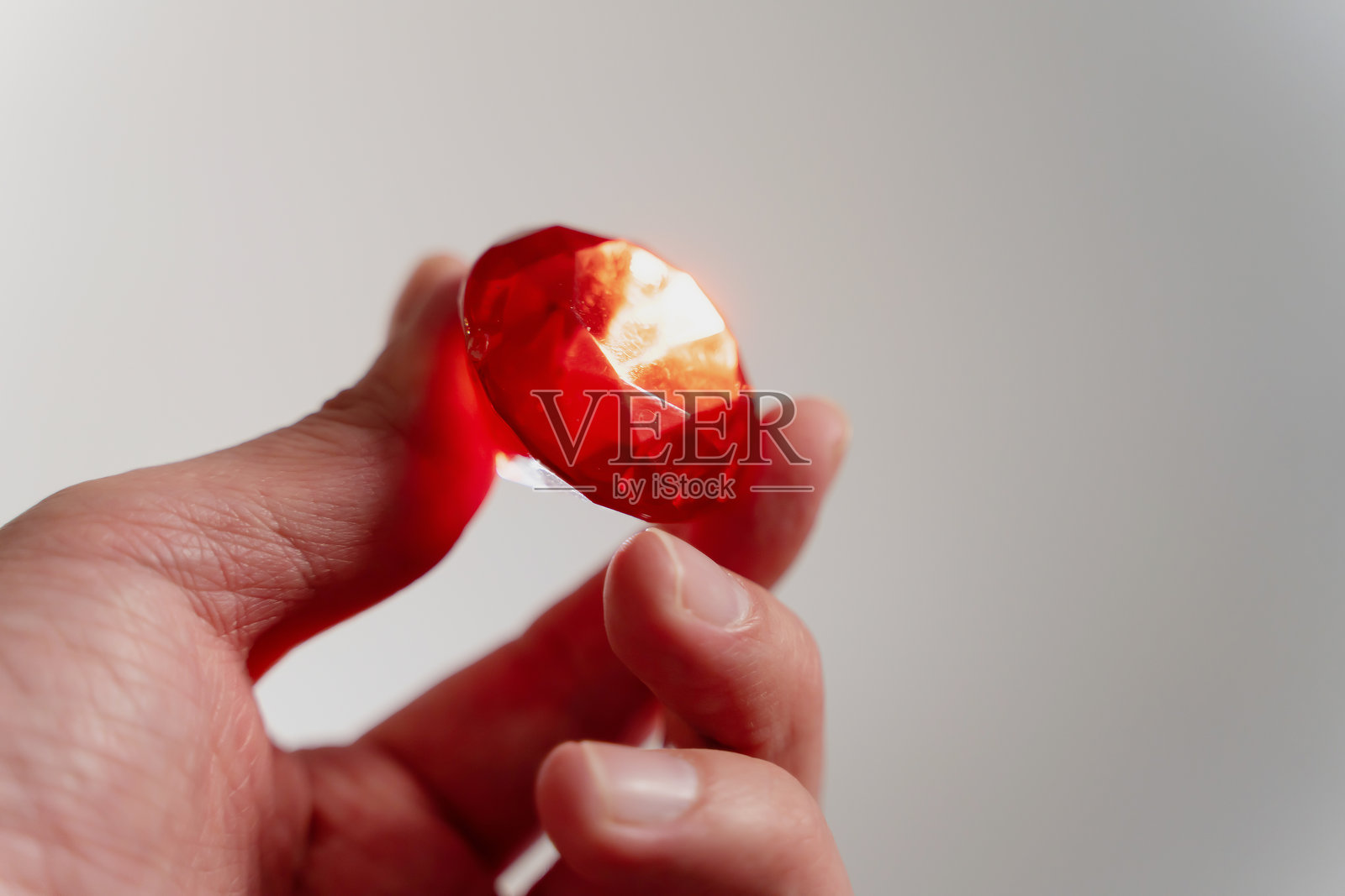 手握红色红宝石钻石,珍贵的水晶宝石在灰色背景上,奢华珠宝概念,奢华红色宝石水晶照片摄影图片