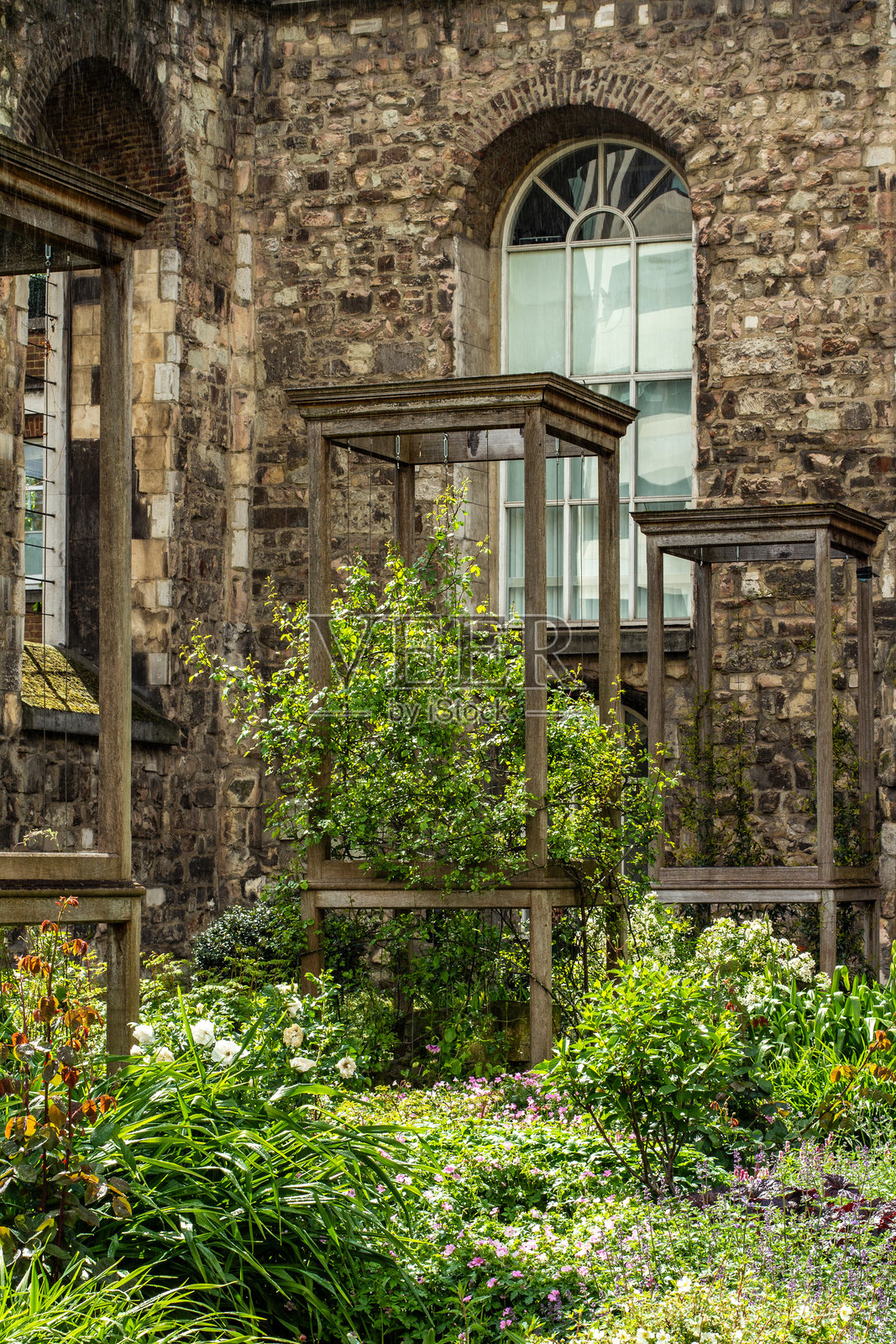 历史悠久的砖墙与生机勃勃的绿色花园和木质结构照片摄影图片