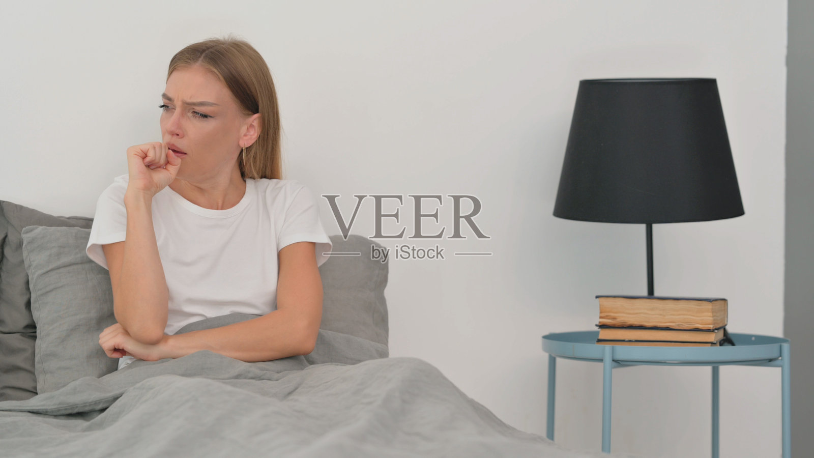 生病的年轻女性坐在床上咳嗽照片摄影图片