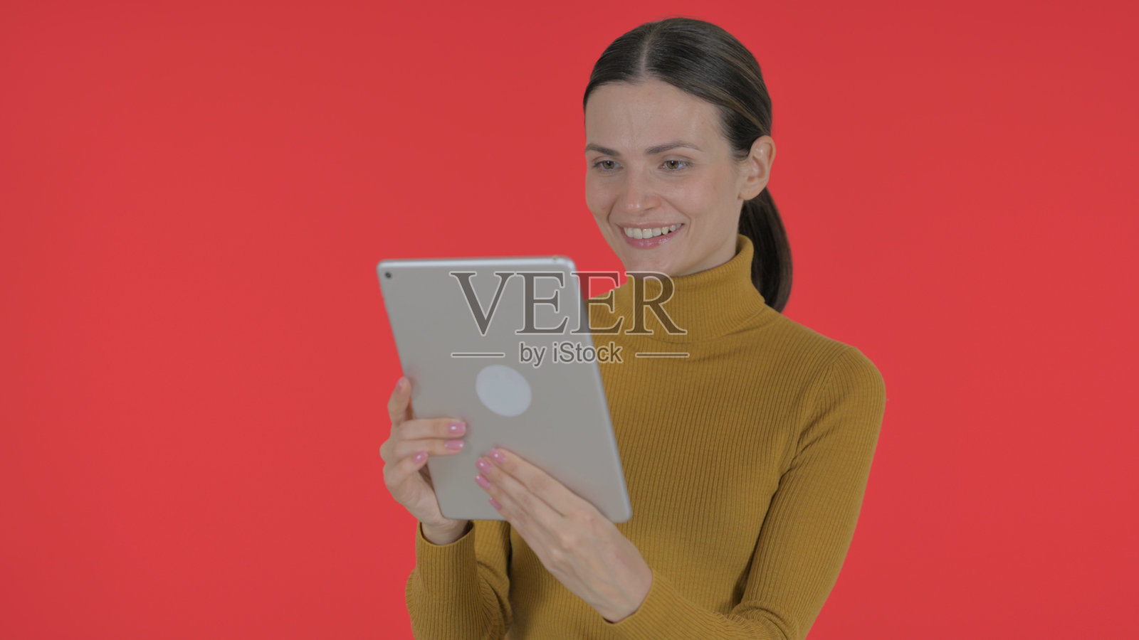 年轻女性在红色背景下用平板电脑进行视频聊天照片摄影图片