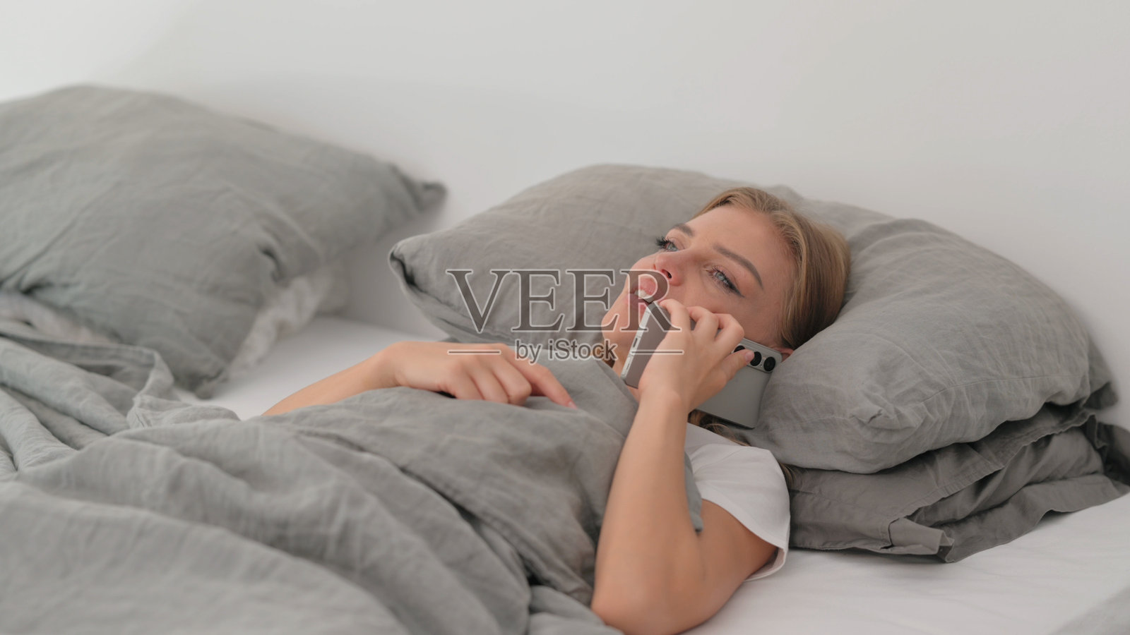 年轻女性躺在床上打电话照片摄影图片