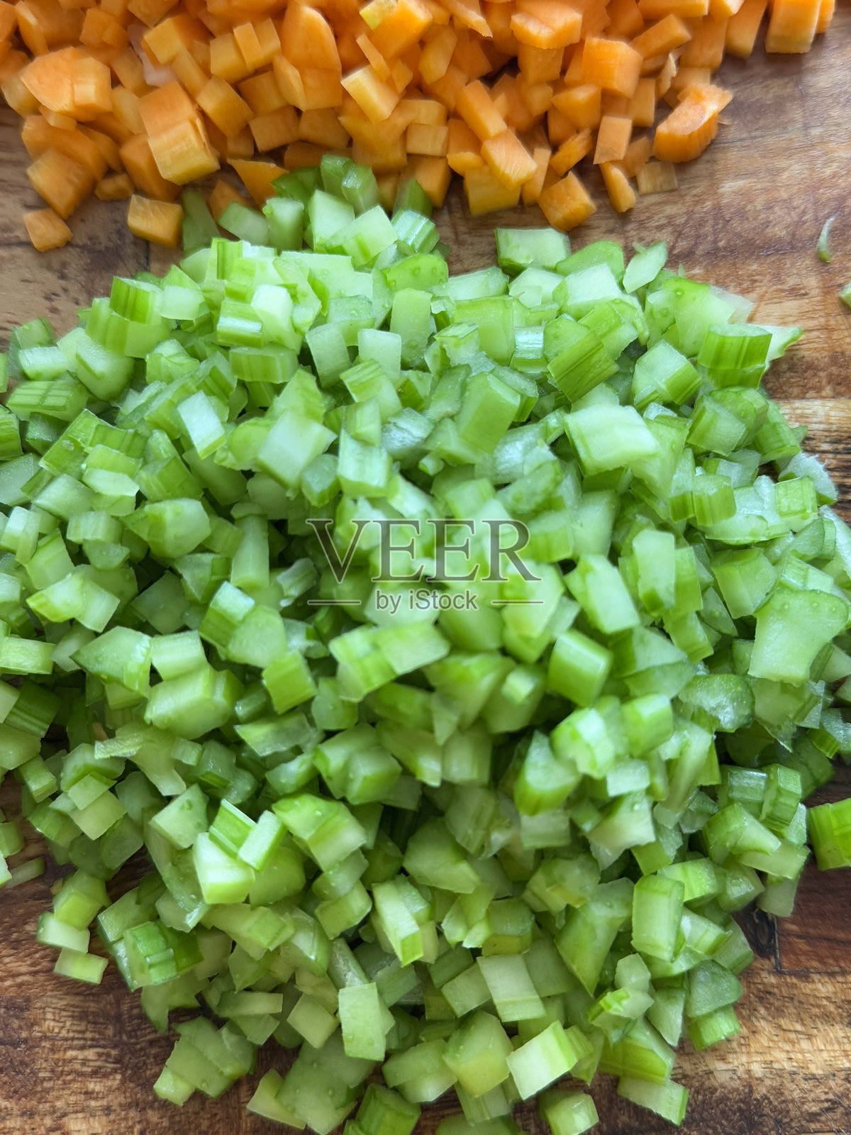 全景图像,展示了木砧板上堆放的细切芹菜和胡萝卜,为意大利肉酱的基础,俯视角度,食品准备概念。照片摄影图片