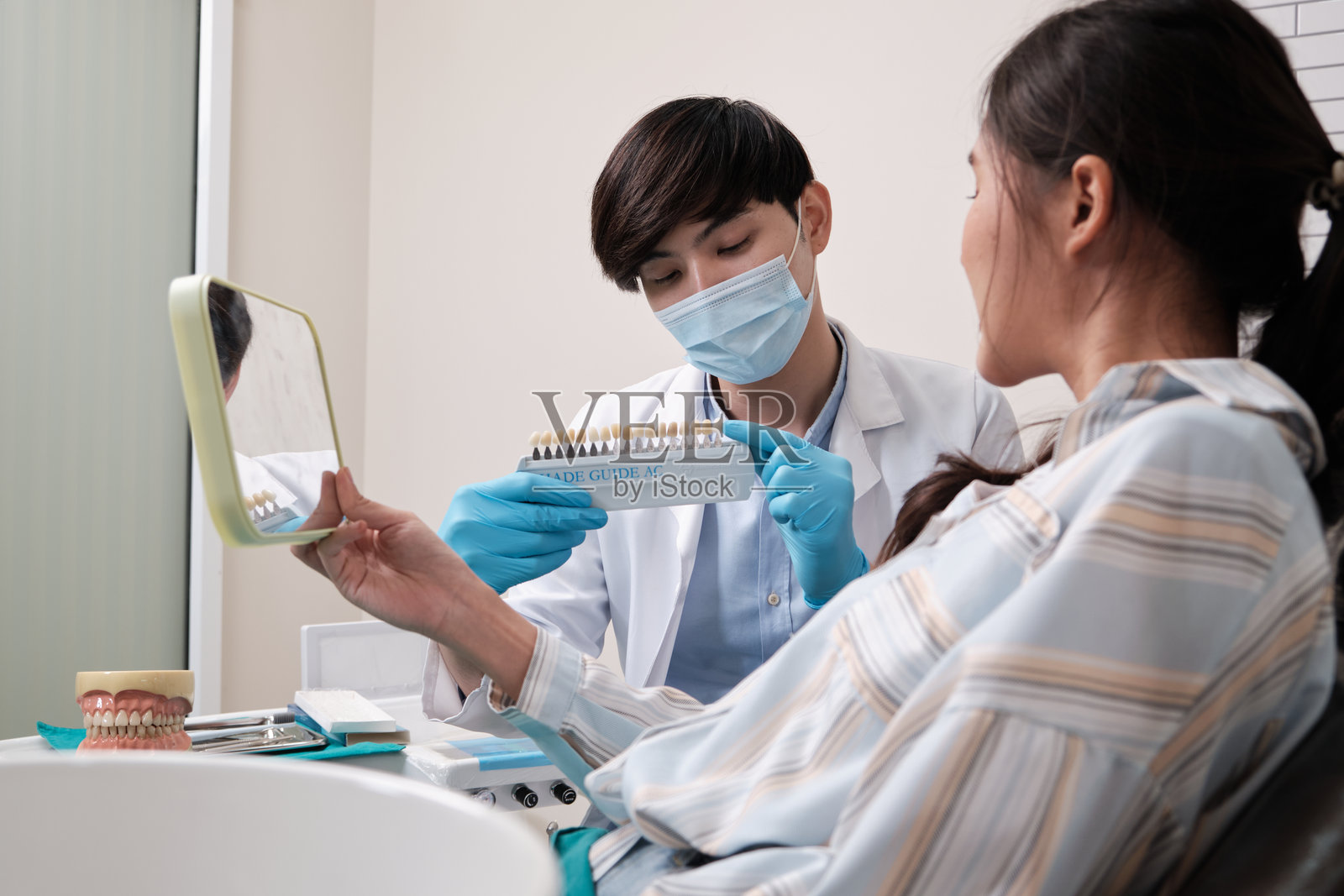 男性牙医向女性患者解释牙齿植体美白的颜色。照片摄影图片