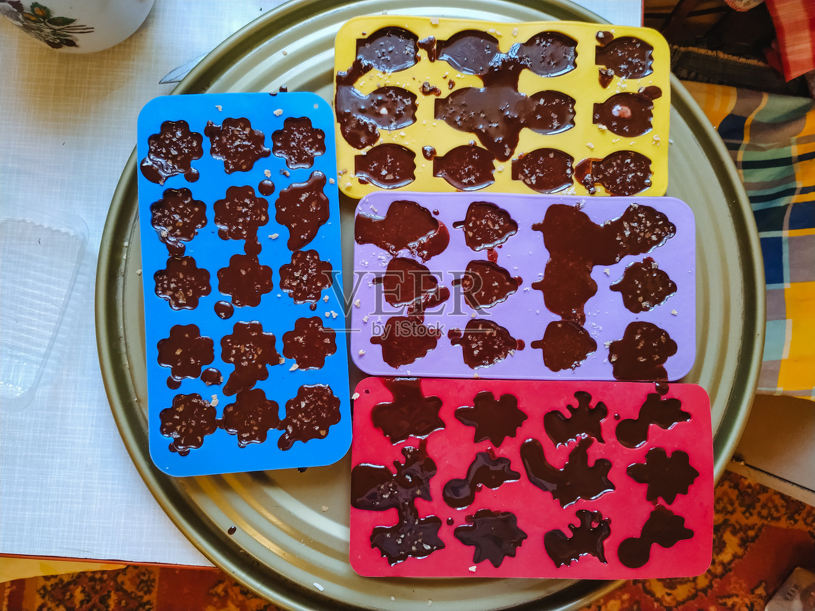 有四个不同颜色的独特托盘,专为制作巧克力冰块而设计,整齐地摆放在盘子上,展示出令人愉悦的色彩组合。照片摄影图片