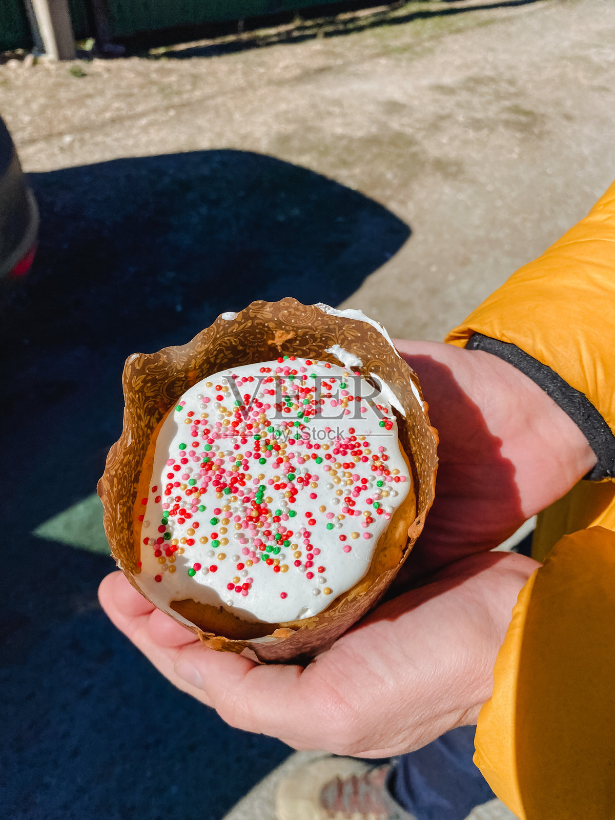 一个人高兴地拿着一个盛满五彩糖屑的冰淇淋蛋筒,在阳光明媚的日子里享受这个美味的甜点,创造出完美的快乐时刻。照片摄影图片