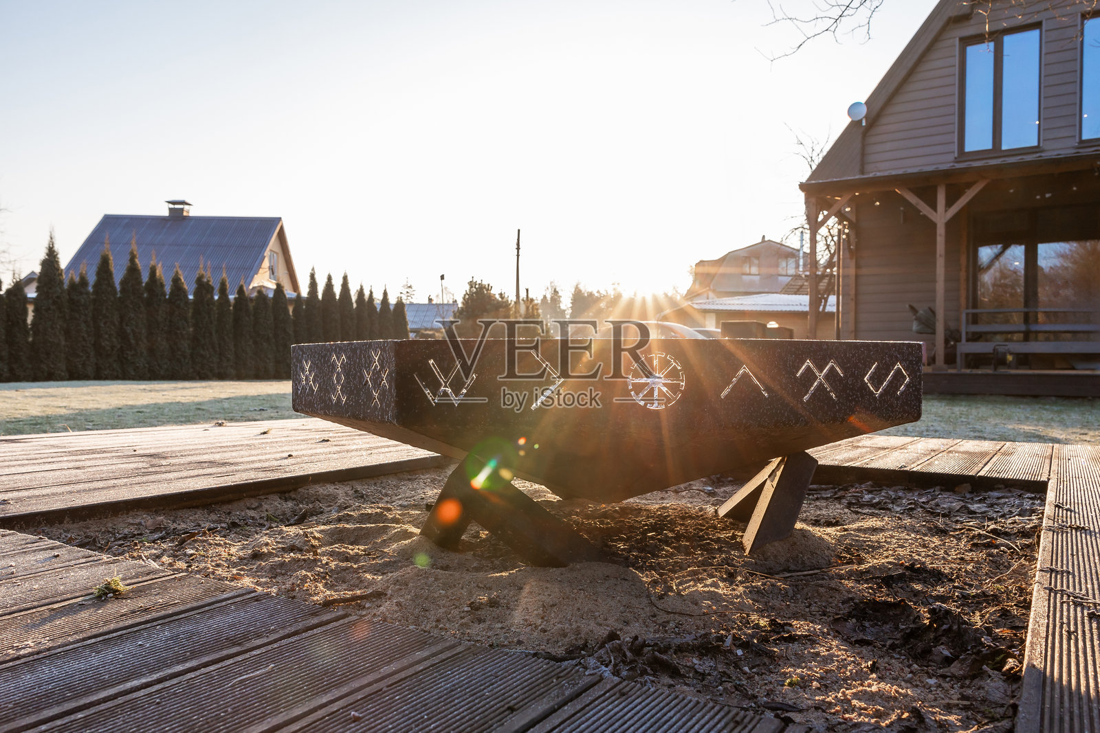 现代火坑位于木质甲板上,周围有常青树和温暖的灯光照片摄影图片