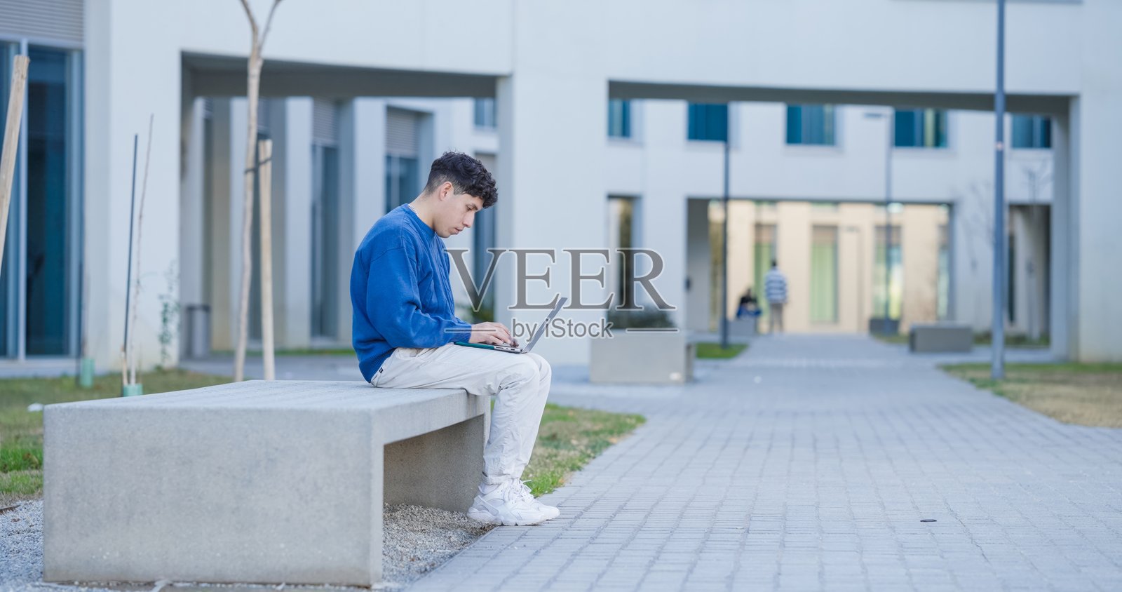 专注的学生在大学建筑外使用笔记本电脑照片摄影图片