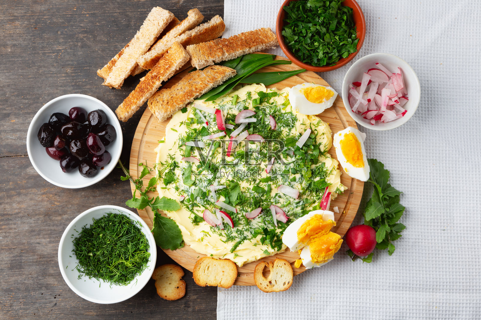 绿色黄油板配新鲜香草、面包片、烤面包、橄榄和小萝卜照片摄影图片