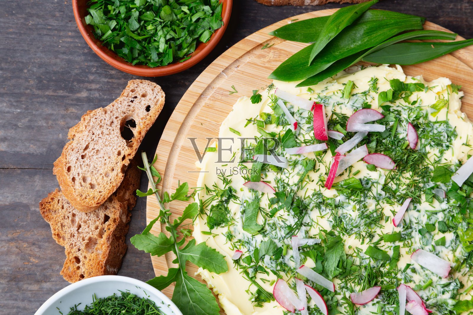 绿色黄油板配新鲜香草、烤面包和萝卜照片摄影图片