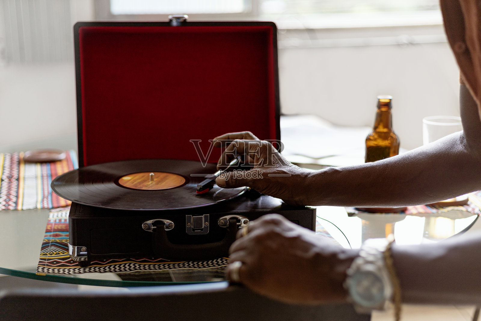 一位优雅的黑人老人在他的巴西家中喝着巴西啤酒,听着桑巴音乐,享受着黑胶唱片的旋律。照片摄影图片
