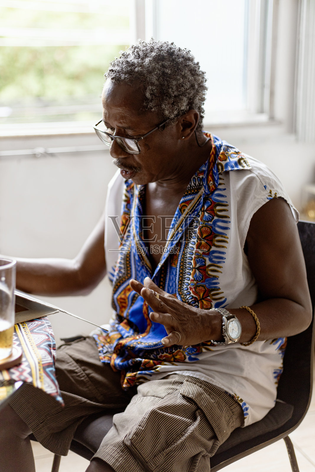 一位优雅的黑人老人在他的巴西家中喝着巴西啤酒,听着桑巴音乐,音乐通过黑胶唱片播放。照片摄影图片