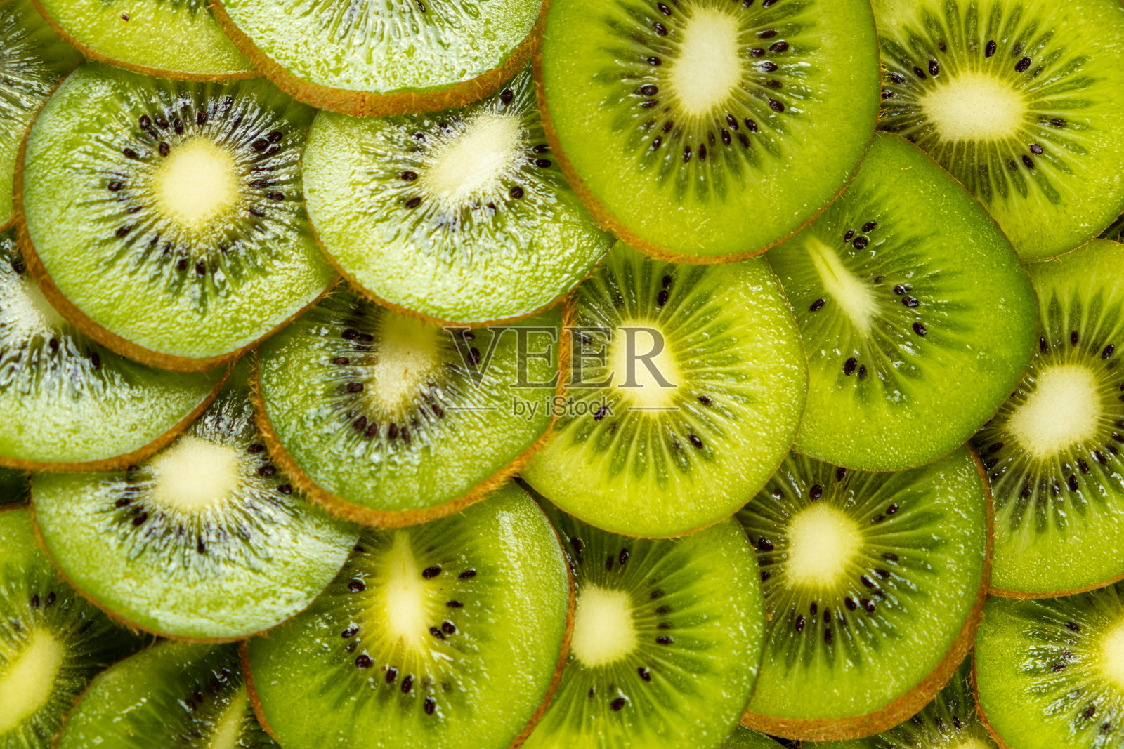 鲜艳的切片奇异果环背景。生机勃勃、清新的热带水果图案,充满多汁的绿色色调。照片摄影图片