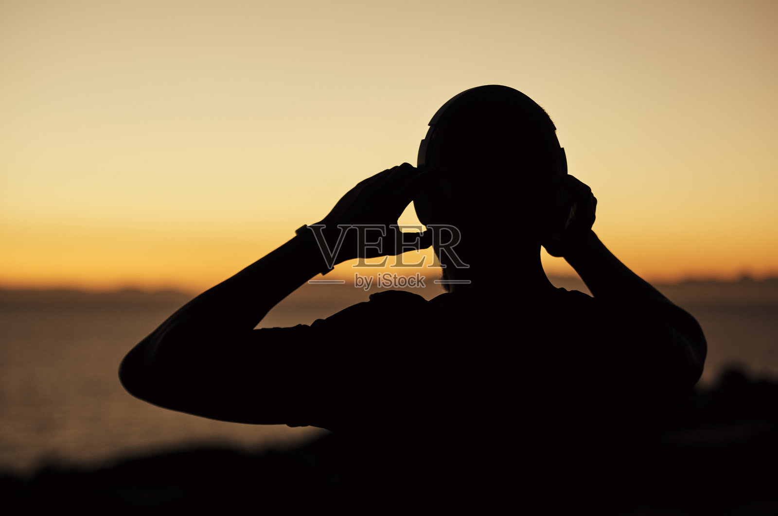 年轻强壮的运动员穿着运动服,戴着耳机听音乐照片摄影图片