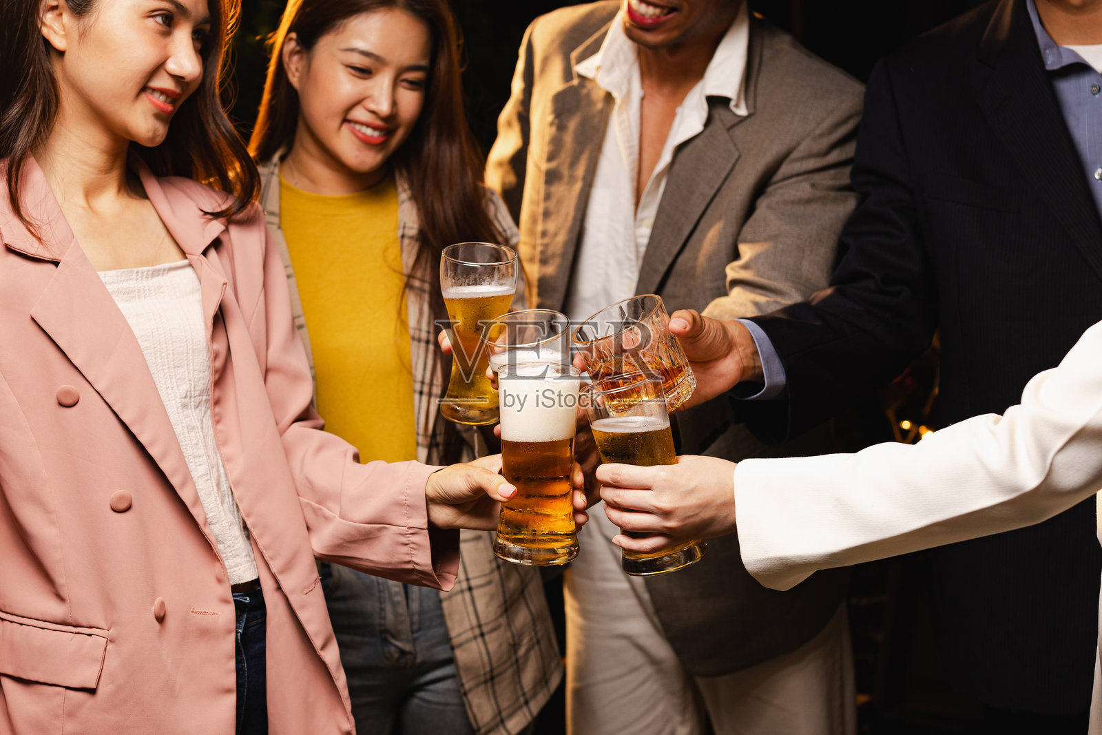 一群朋友在夜晚庆祝时碰杯,节日庆祝。照片摄影图片