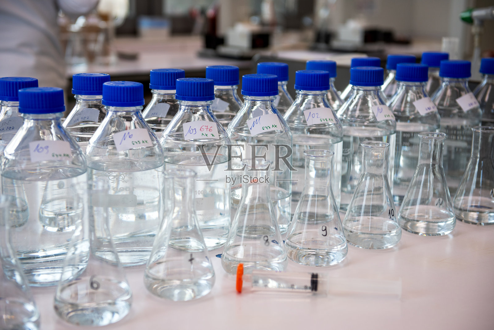 实验室设备。白色桌子上的实验室储存瓶,配有蓝色聚丙烯瓶盖。照片摄影图片