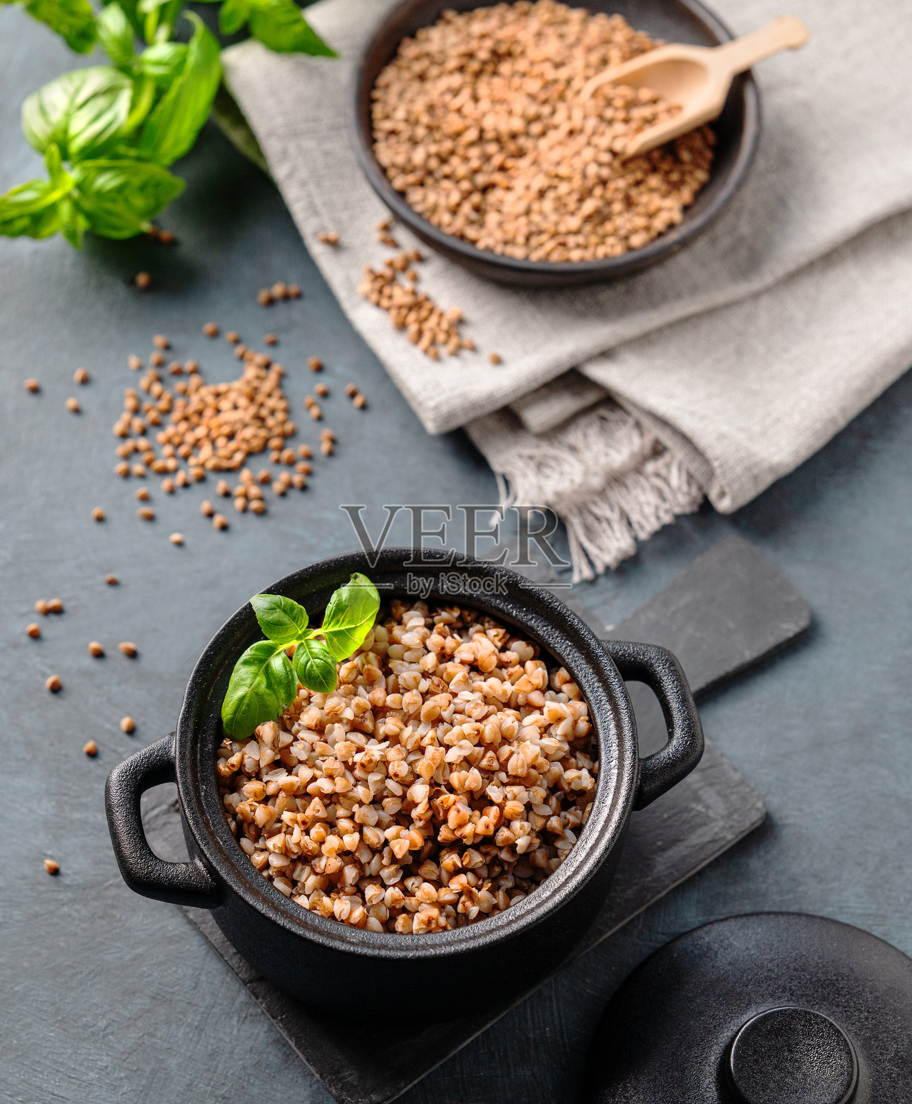 黑底黑锅里的荞麦粥,配上生谷物和草药。照片摄影图片