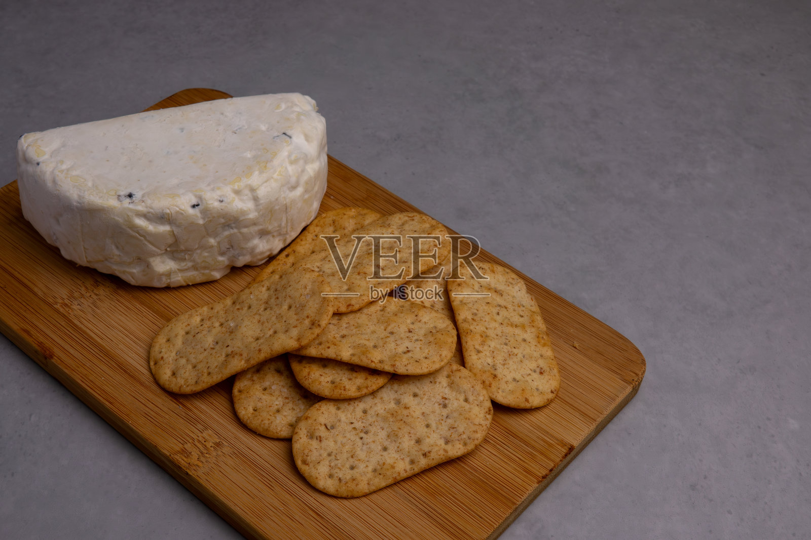 奶油奶酪与脆饼干一起放在木砧板上,带来愉悦的小吃体验照片摄影图片