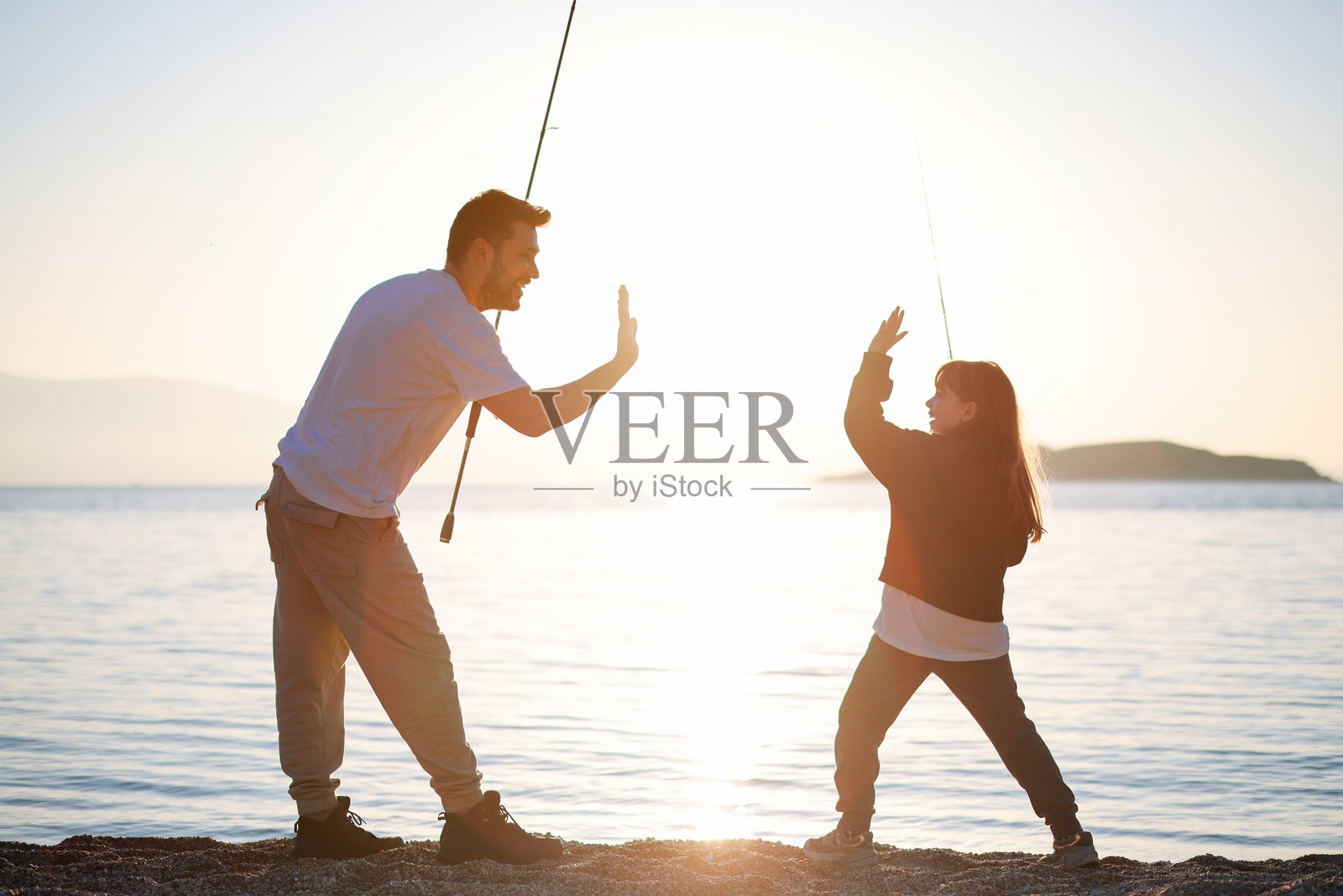 一位年轻父亲在海边与他的小女儿一起钓鱼照片摄影图片