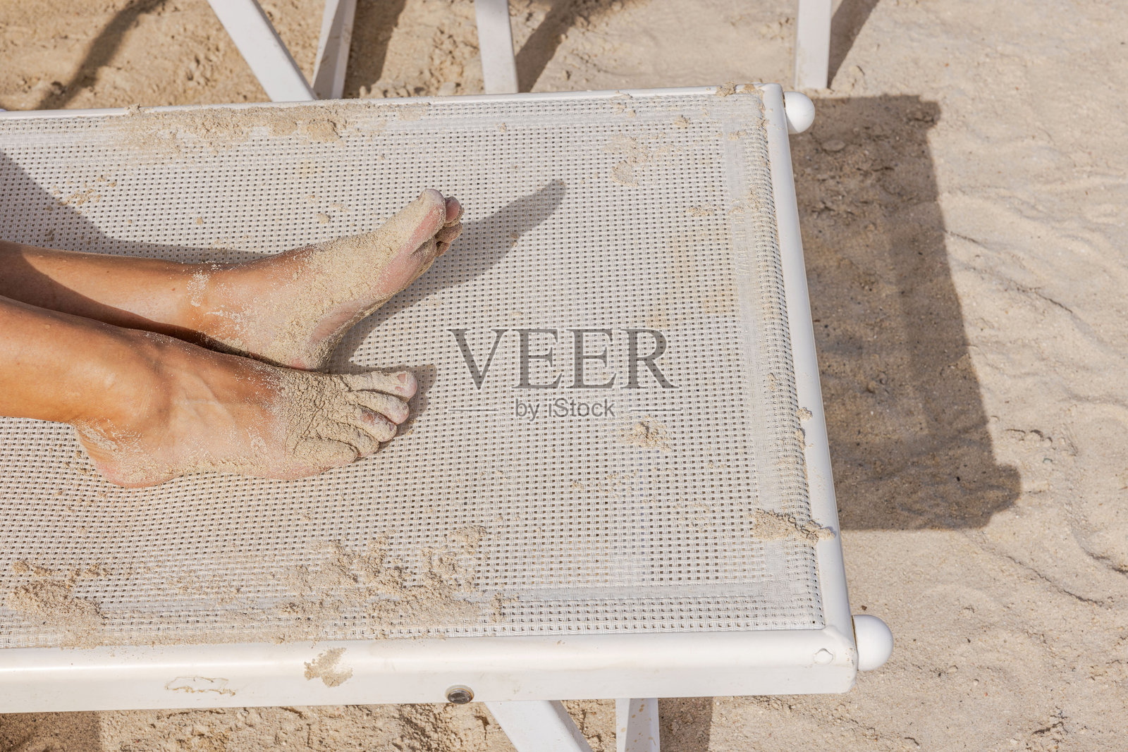 沙滩上细腻的沙子和温暖的热带天气下,阳光明媚,沙滩椅上放松的沙滩脚。库拉索。照片摄影图片