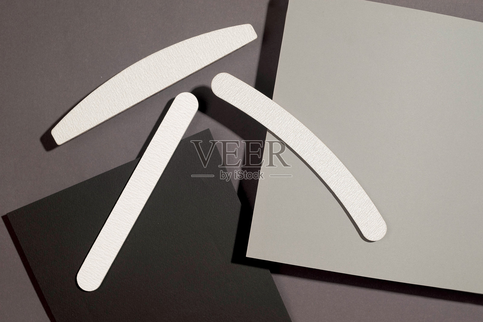 在深灰色底色上设置不同形状和不同刚度的灰色指甲锉,等距。修甲工具照片摄影图片