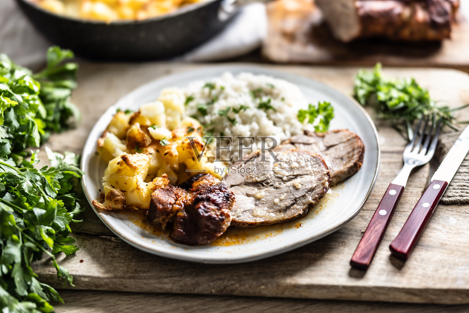 一份多汁的烤颈肉,放在盘子里,配以土豆、米饭和烤食品的酱汁。照片摄影图片