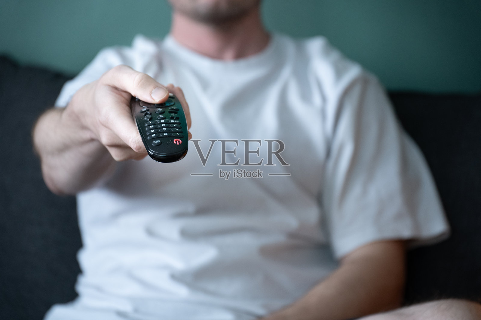 休闲男子手中握着的电视遥控器特写照片摄影图片