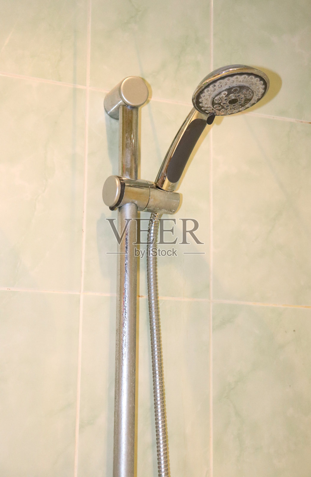 浴室墙壁上带有水垢沉积的淋浴头和软管支架照片摄影图片