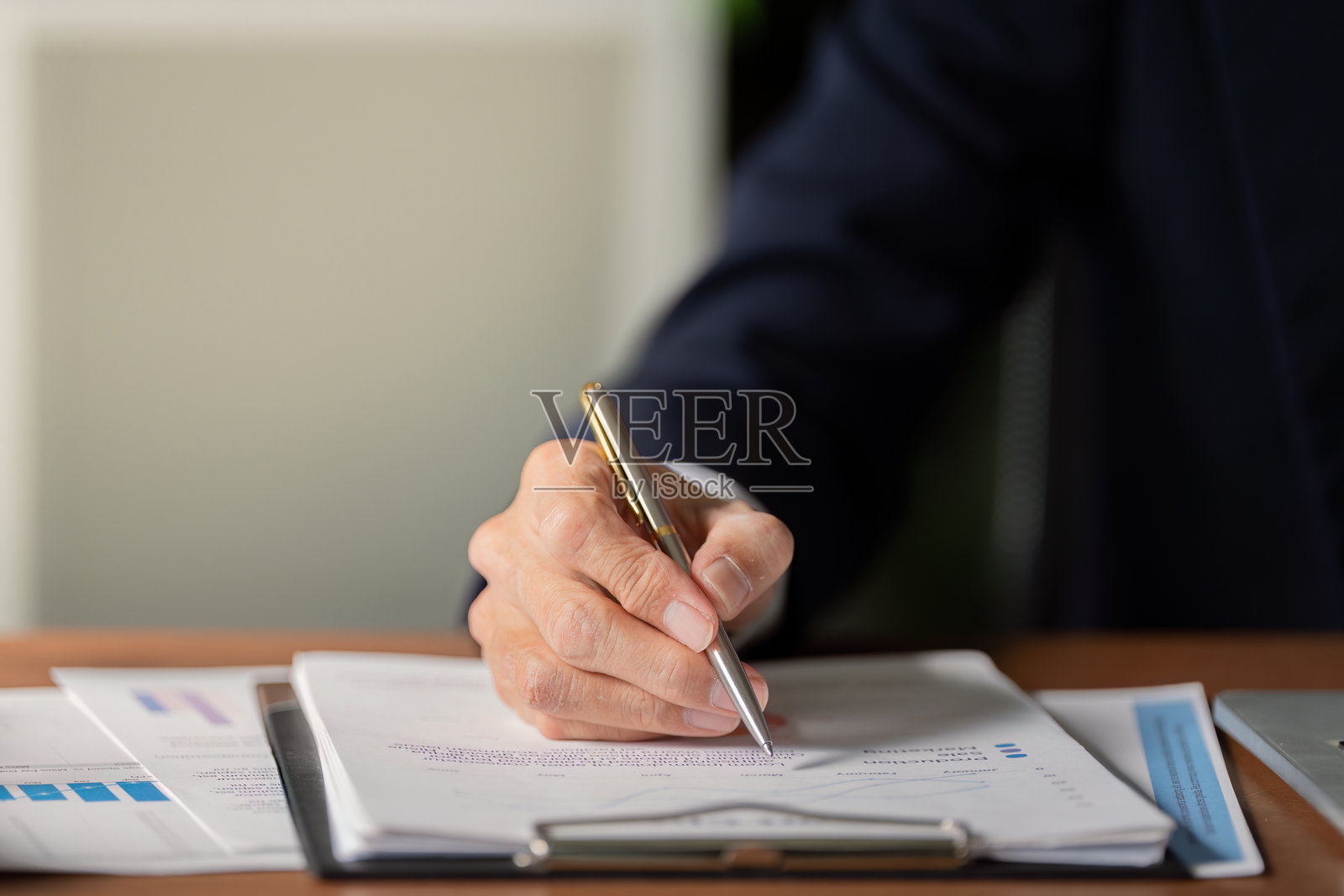 高级会计师在现代办公室审查财务文件并在夹板上写笔记照片摄影图片