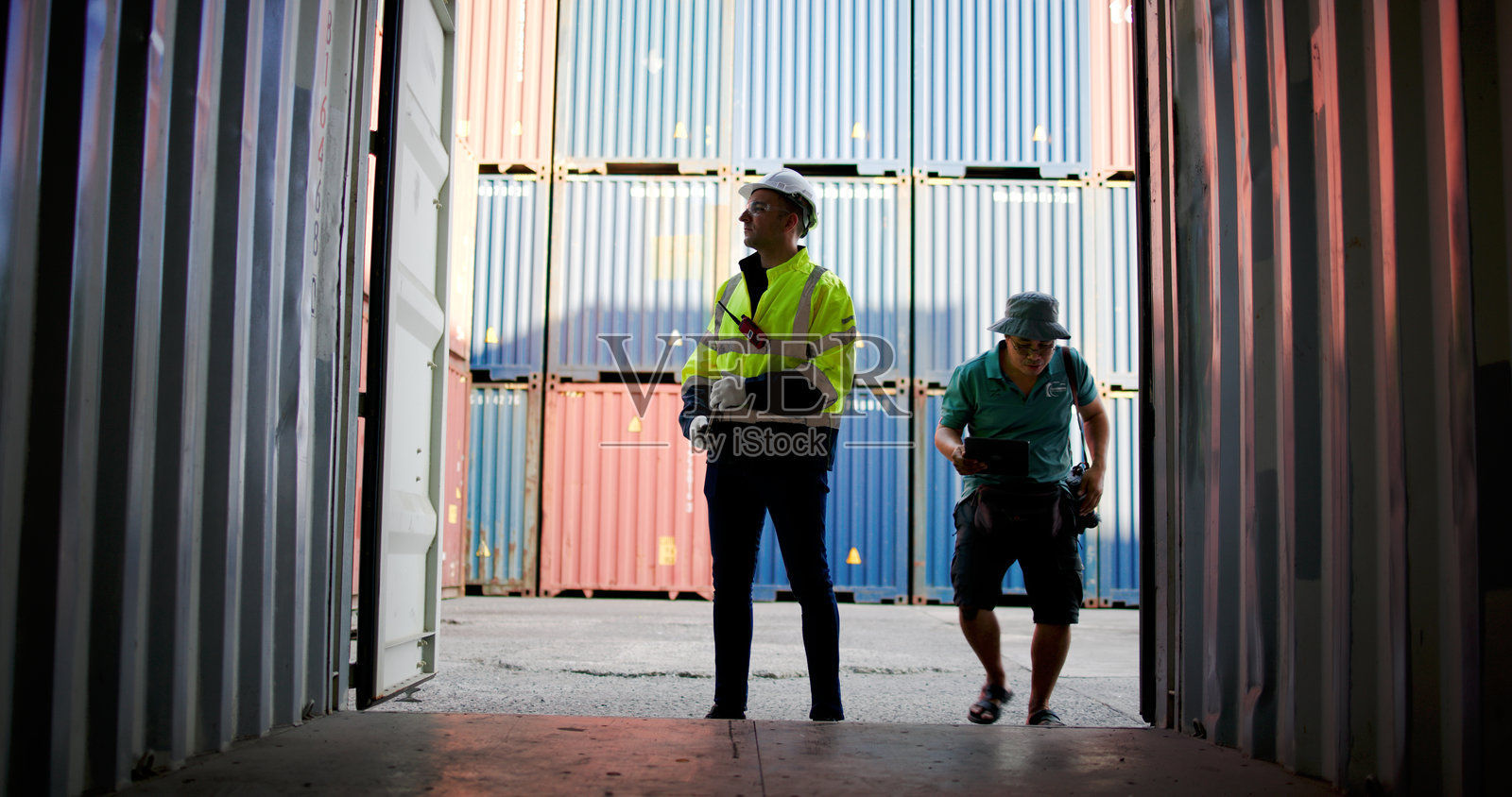 蓝领工人在商业码头工作。男性港口工人打开货运集装箱以检查集装箱的准备情况。照片摄影图片