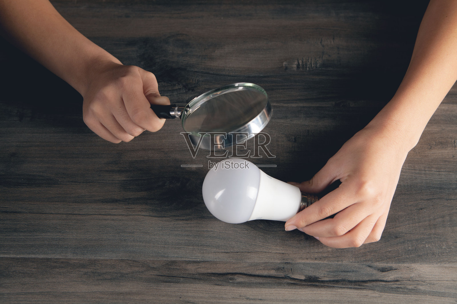 女人用放大镜观察灯泡照片摄影图片