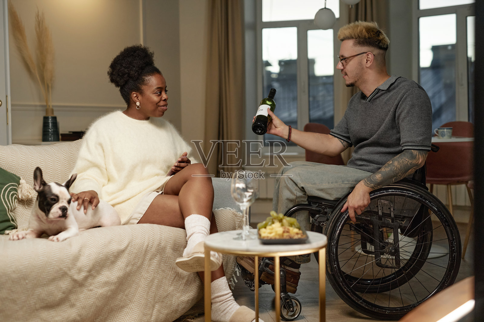 男子使用轮椅,向在家中享用红酒的黑人女性示意浪漫约会。照片摄影图片