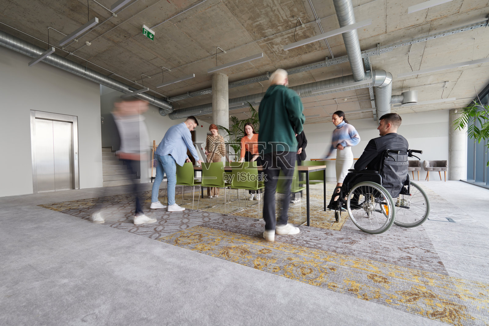 一位坐在轮椅上的主管带领的商务团队在现代办公室准备会议。照片摄影图片