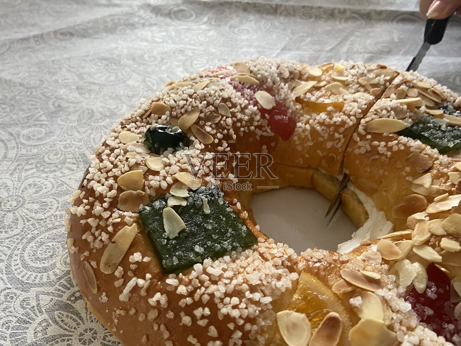 传统的三王节蛋糕,配有糖果水果、杏仁和糖霜,正在被切片照片摄影图片