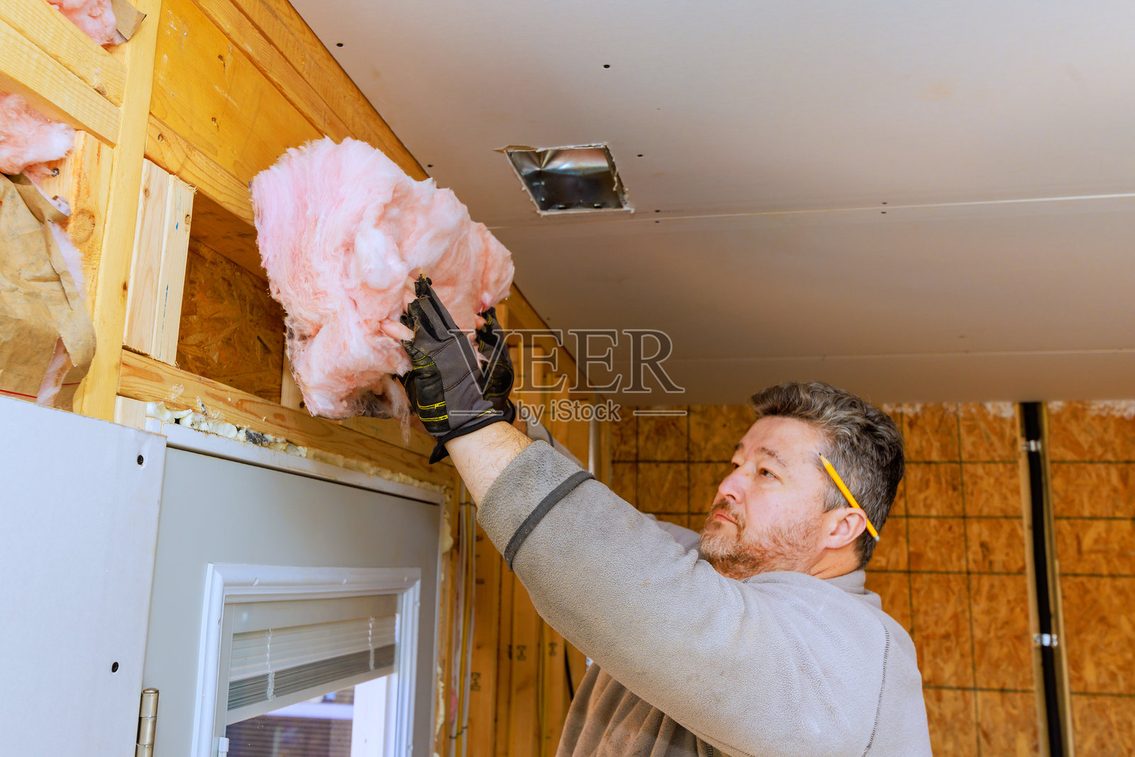 男子在冬季的家居装修项目中使用粉色保温材料为房间进行隔热。照片摄影图片