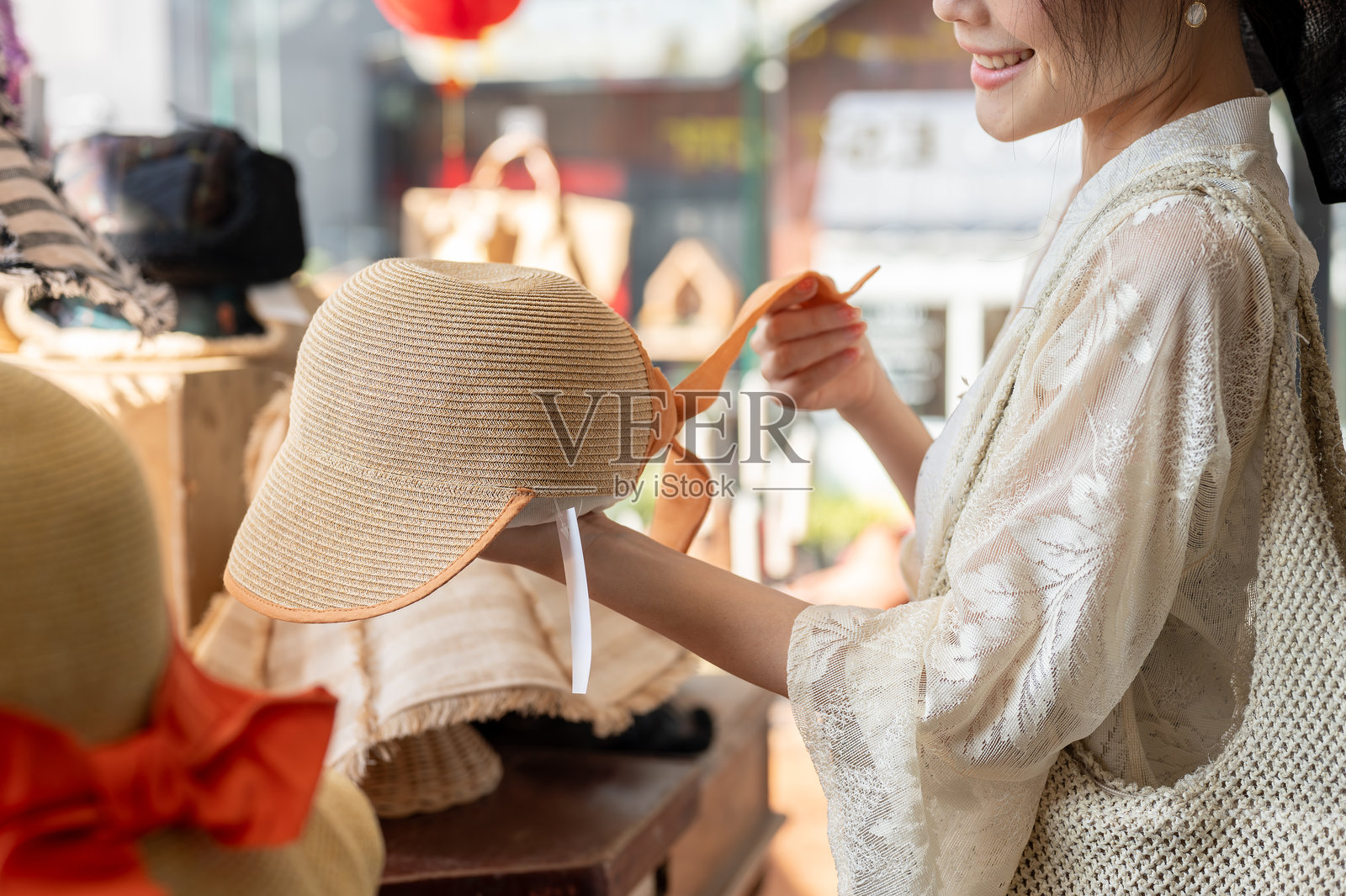 一位快乐的亚洲女性在帽子店仔细挑选商品,享受她的购物狂欢。照片摄影图片