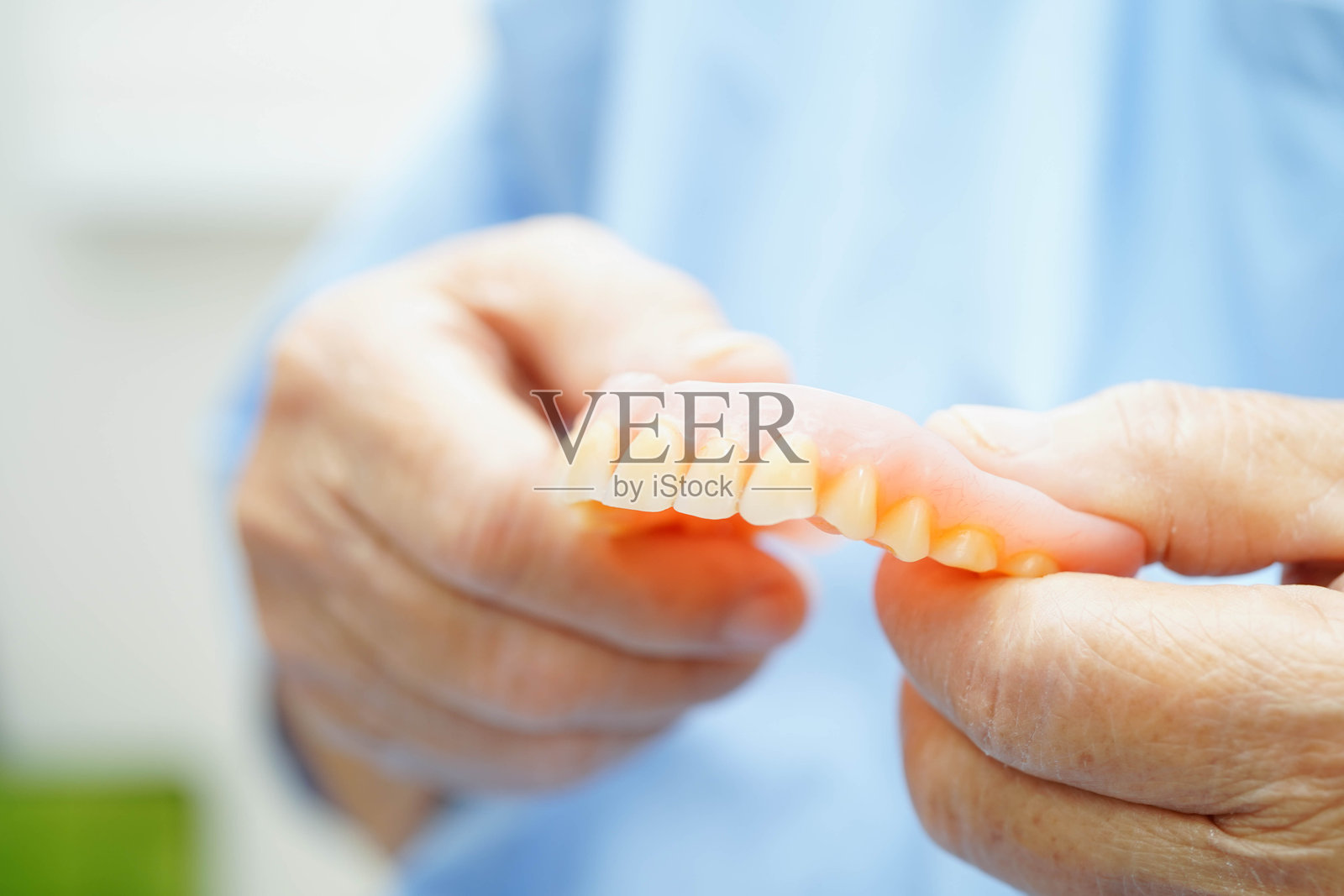 亚洲老年女性患者将假牙放入嘴中以咀嚼食物。照片摄影图片