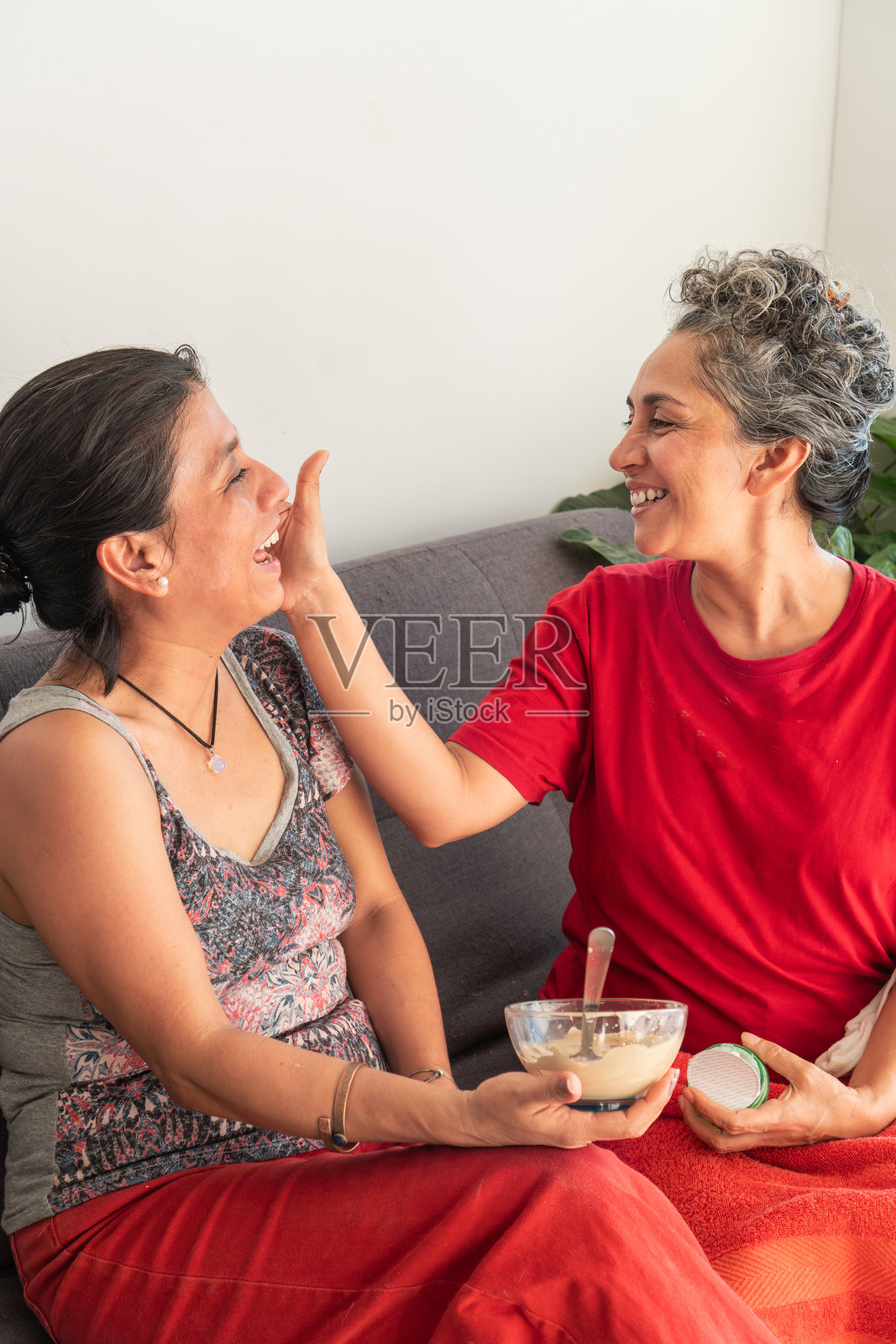 美容师为微笑的女性涂抹面膜照片摄影图片