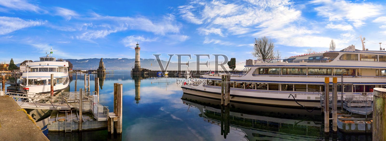 德国巴伐利亚林道港口的全景,船只、灯塔和狮子雕像。照片摄影图片