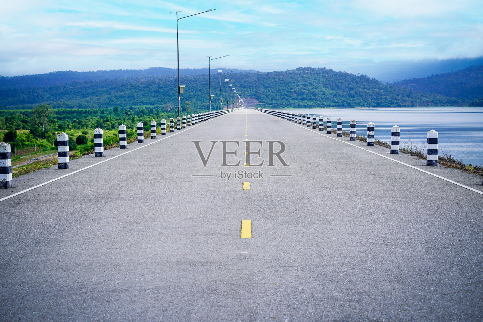 通往山脉的道路,旁边有湖泊,晴天的蓝天映衬着泰国普拉清布里的Naruebodindrachinta水库。照片摄影图片